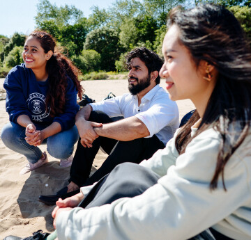 3 students sitting on a beach