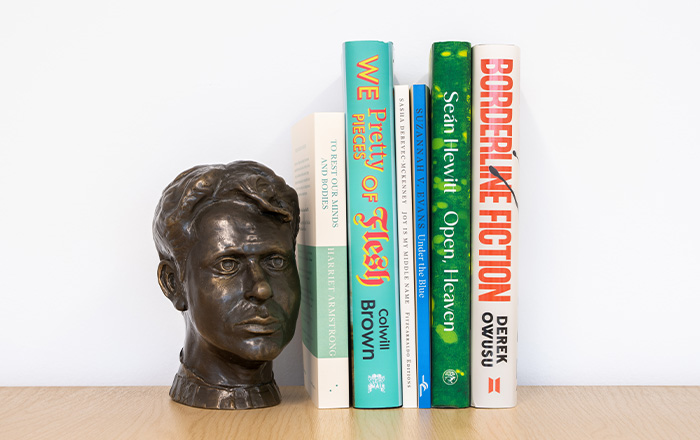 Bookshelf image of the 6 book spines accompanied by bronze bust of Dylan Thomas